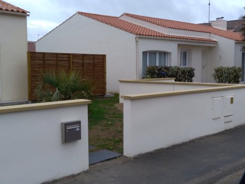 Reprise d’un muret de clôture avec couvertines crème et panneaux bois aux Sables-d’Olonne